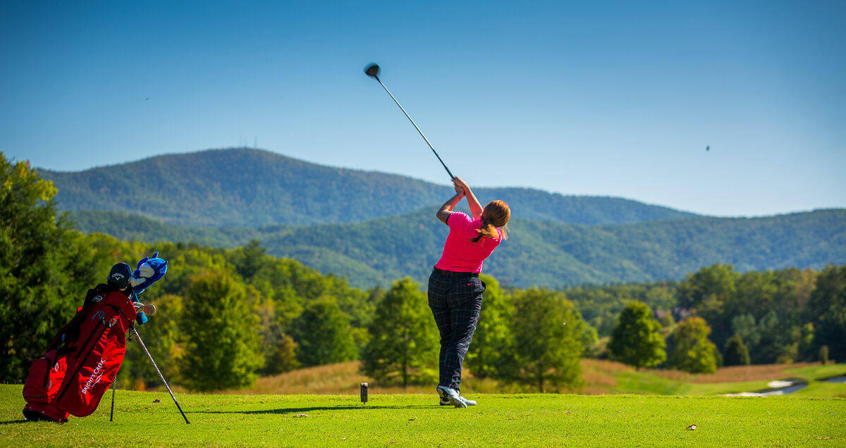 Woman playing golf with Blue Ridge Mountain views at Bright's Creek Club
